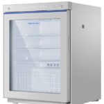 A metallic Haier medical refrigerator with a large glass door, a digital display on top, and a wire basket at the bottom.